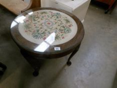 A glass topped coffee table with tapestry inset and on Queen Anne style legs
