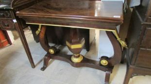 A mahogany fold over table on unusual base with gilded swan heads