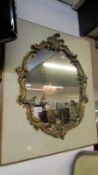 A gilt framed shield shaped mirror mounted on a back board