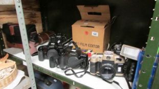 A shelf of camera's including Cannon and Olympus
