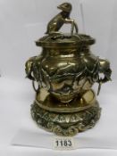 An 19th century Oriental brass sensor on stand surmounted dog and with lion head handles