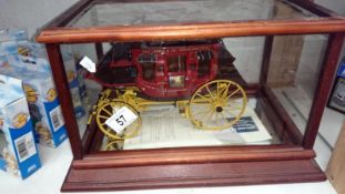 A Franklin Mint Wells Fargo stage coach in glass display cabinet