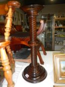 A dark stained turned wooden torchere stand