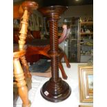 A dark stained turned wooden torchere stand