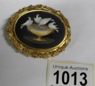An ornate yellow metal brooch with marble depiction of doves (rim tests as gold)