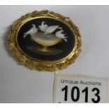 An ornate yellow metal brooch with marble depiction of doves (rim tests as gold)