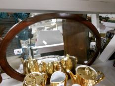 An oval bevel edged mirror in mahogany inlaid frame