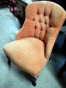 A peach upholstered nursing chair with deep buttoned back and Queen Anne legs