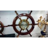 A brass ships clock mounted inside a ships wheel