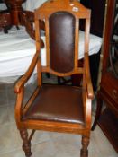 An Edwardian oak carver chair with leather seat and back panel
