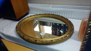 A gilded oval wall mirror