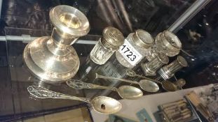 A silver candlestick, silver topped jars & 4 silver spoons etc.