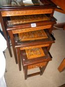 A nest of 4 carved Oriental tables with glass tops