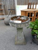 A stone bird bath on stand