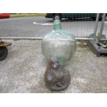 A large bulbous glass vase and a garden Buddha
