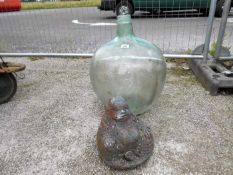 A large bulbous glass vase and a garden Buddha