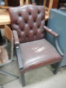 An Edwardian leather armchair with buttoned back