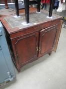 A dark wood stained 2 door cabinet with green leather inset top