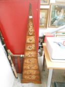 A dark wood stained pyramid chest of drawers with gold painted decoration