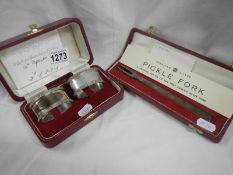 A cased pair of silver napkin rings and a cased silver pickle fork