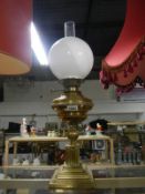 A brass oil lamp with shade and chimney