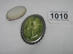 A silver mother of pearl brooch and a green stone brooch