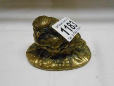 An antique brass chick paperweight with glass eyes,