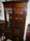 A darkwood stained astragal glazed display cabinet with cupboard base