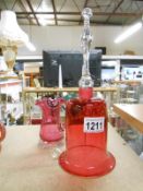 A cranberry glass bell and a cranberry glass jug