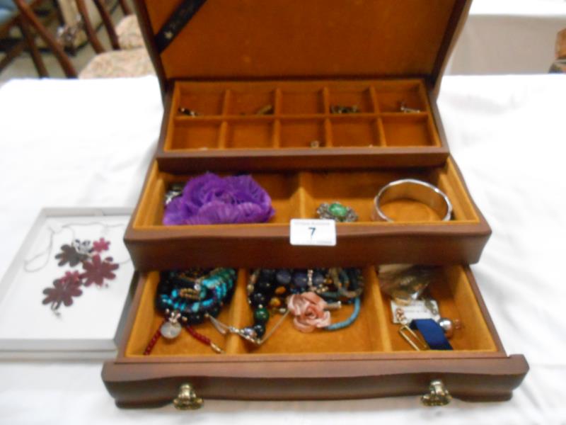 A wooden jewellery box with a quantity of costume jewellery