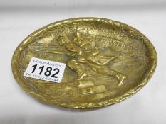 An old brass dish depicting a WW1 soldier charging up steps,