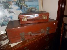 A small vintage suitcase and a vintage suitcase