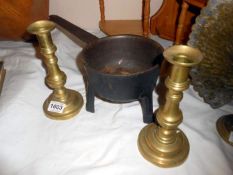 A pair of brass candlesticks and heavy saucepan on tripod feet