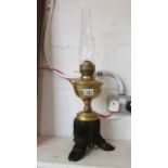 A brass oil lamp with taxidermy wild boar foot base