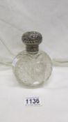 A cut glass perfume bottle with silver top
