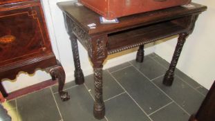 A dark oak side table with carved legs and side panels