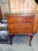A 1950s walnut veneered 3 drawer bedside with glass top and Queen Anne legs