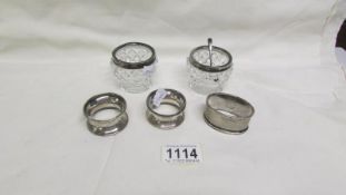 3 silver napkin rings and 2 silver rimmed salts with spoon