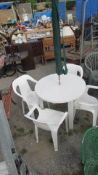 A white garden table, 4 chairs and parasol