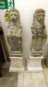 A pair of garden lions on pedestals & holding shields