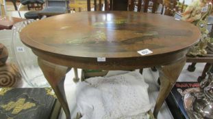 An oval coffee table inlaid with an oriental scene