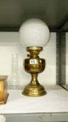 A brass oil lamp with shade and chimney