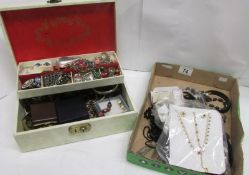 A white jewellery box of costume jewellery together with a tray of mostly black costume jewellery