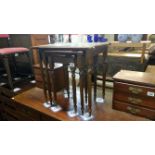 A nest of 3 dark wood table with glass tops and green/gold leather insets