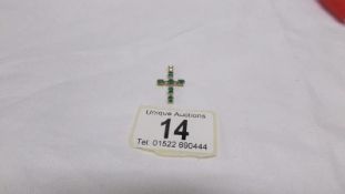 An emerald and diamond yellow gold cross