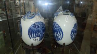 A pair of Chinese blue and white vases on stands and with dragon features