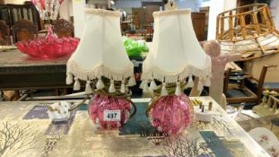 A pair of cranberry glass lamps with shades