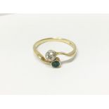 An 18ct gold diamond and emerald cross over ring,