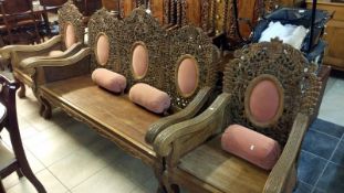 A heavily carved teak 3 piece suite comprising settee and 2 chairs