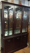 A modern dark wood stained display cabinet with cut glass doors and mirror back